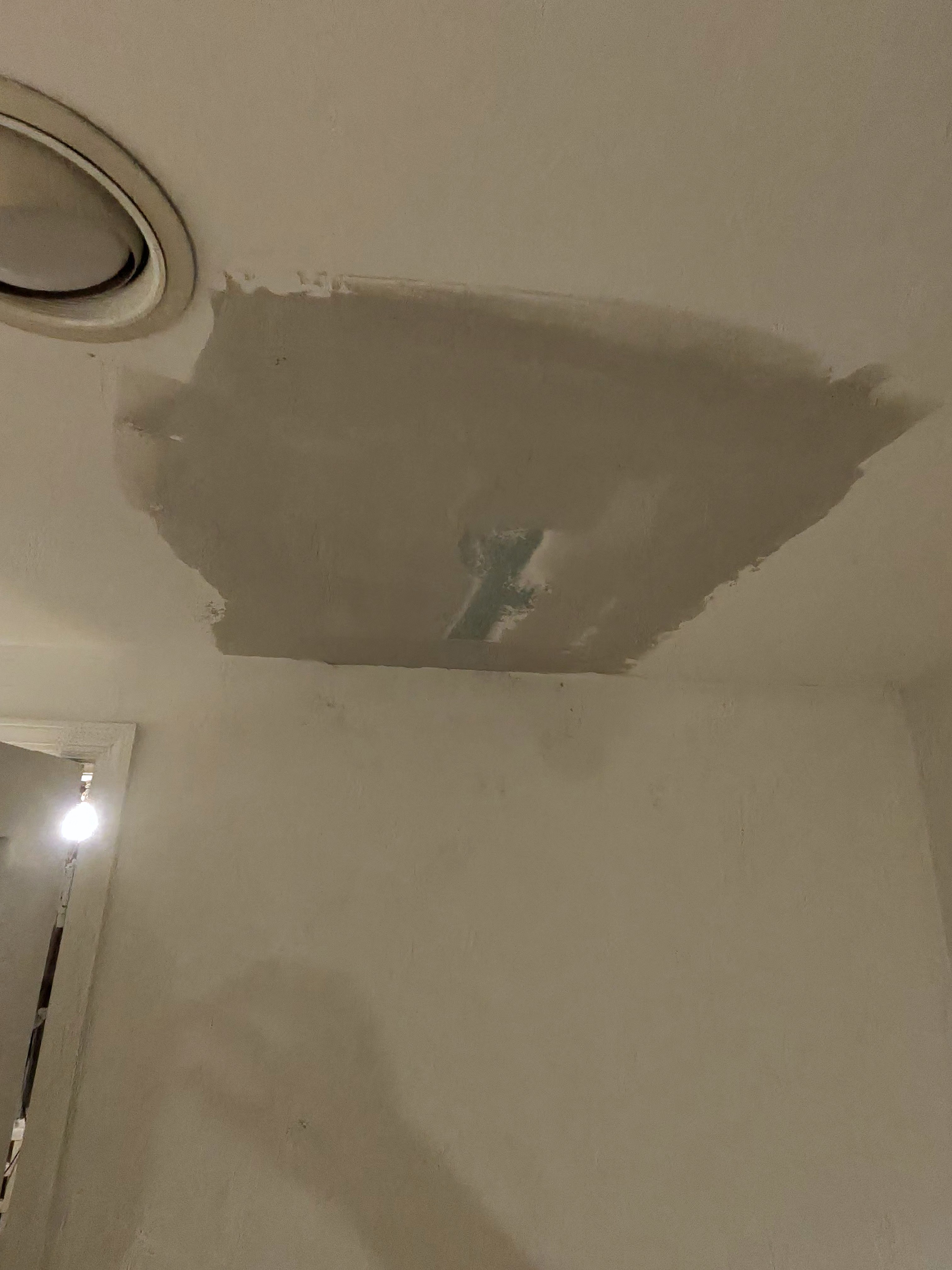 Ceiling with a freshly patched and skim-coated drywall repair ready for paint